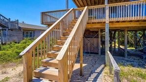 A wooden staircase leading to a deck with a railing, surrounded by sand and vegetation. - Yankee Clipper 204: Oceanfront, balcony, ocean views (Avon)