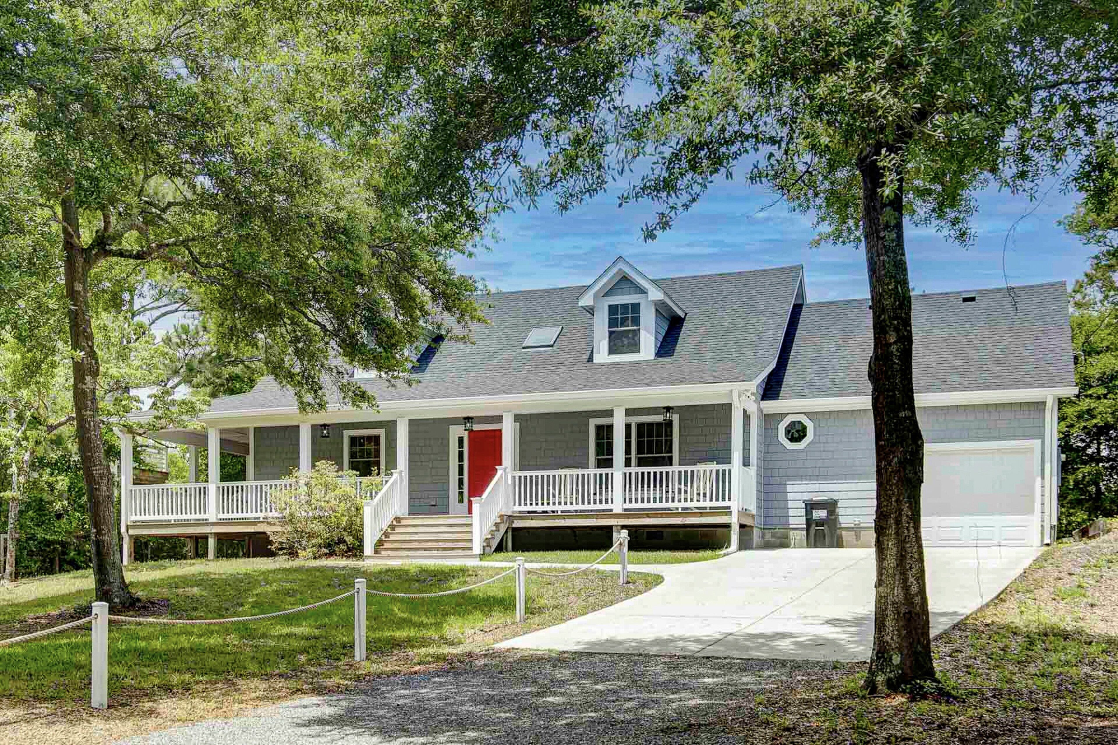 A two-story house with a front porch, a red door, and a garage.