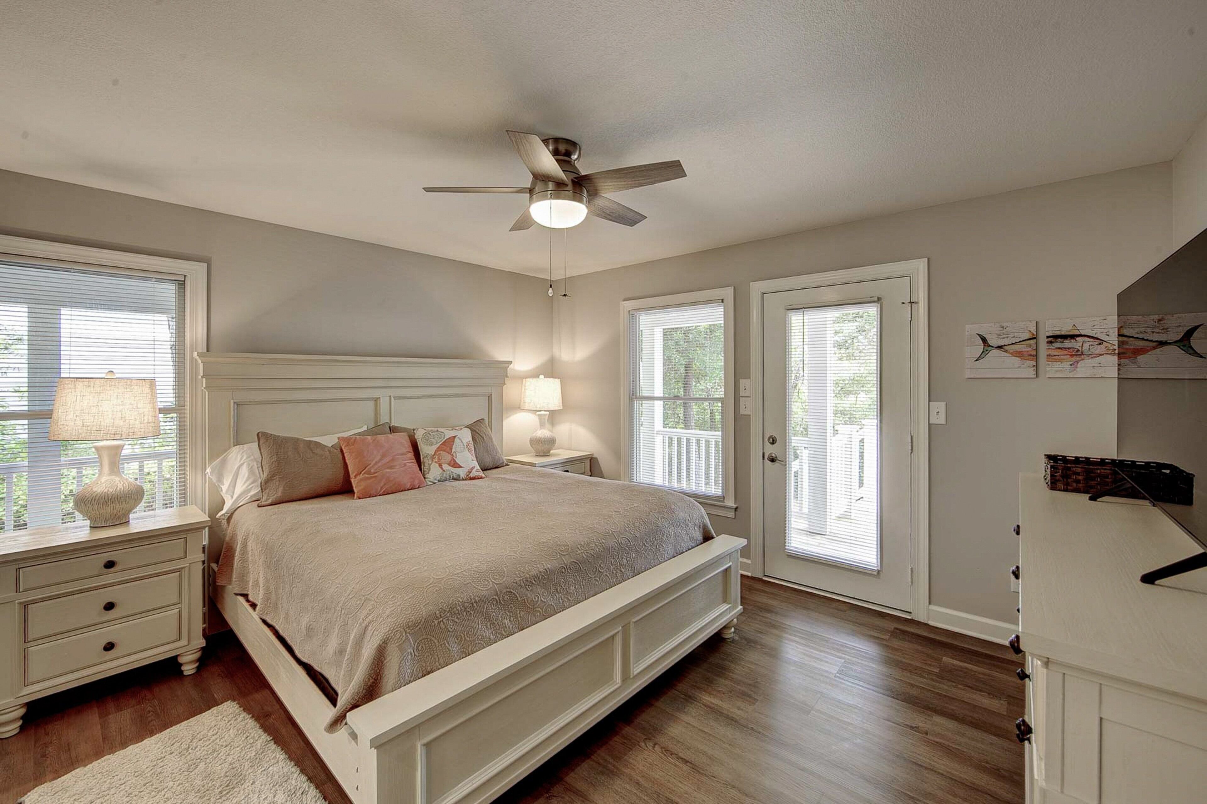 A bedroom with a bed, nightstands, a ceiling fan, and a door leading to a balcony.