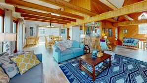Ein geräumiges Wohnzimmer mit einem blauen Sofa, Holzbalken und einem gemusterten Teppich.