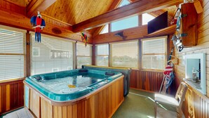 Ein Holzhütten-Interieur mit Whirlpool, Holzwänden und großen Fenstern.