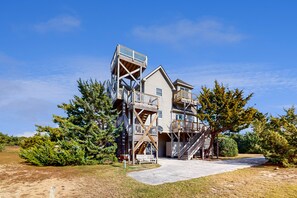 A multi-story building with a central staircase, balconies, and a wooden deck. - Lakefront dog-friendly home w/private hot tub, fireplace, outdoor pool & tennis (Waves)
