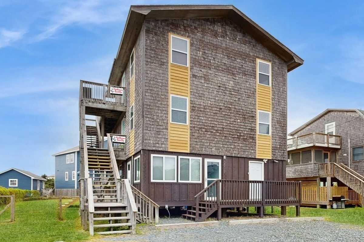 A multi-story building with a wooden exterior, a balcony, and a staircase leading to the upper levels.