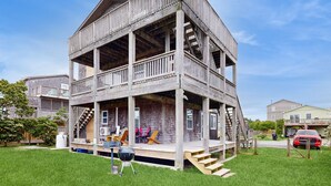 A two-story wooden house with a balcony, a barbecue grill, and outdoor seating. - Tarpon Drive Hideaway: dog-friendly duplex with balcony (Avon)
