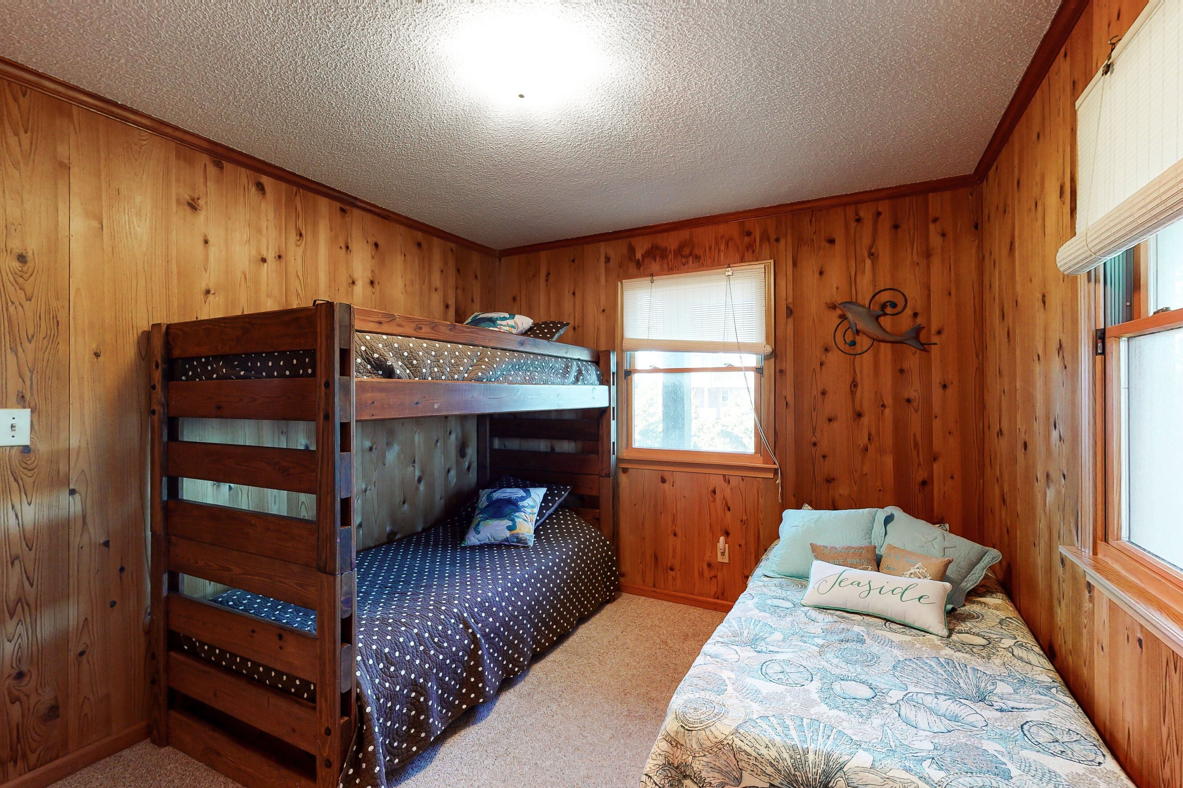 A bunk bed with a polka dot bedspread and a window with blinds.
