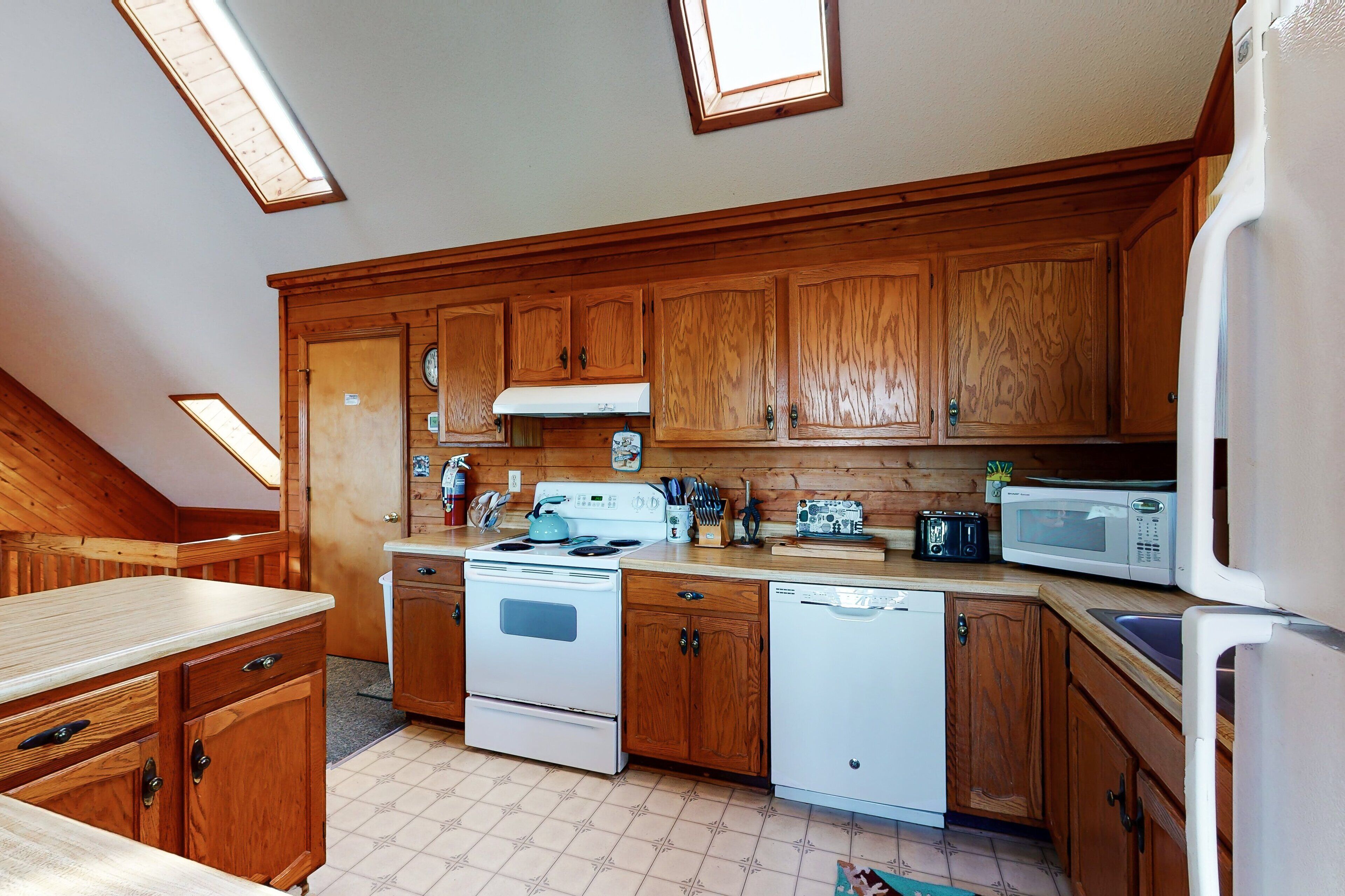 A kitchen with wooden cabinets, a stove, a microwave, and a dishwasher.