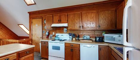 A kitchen with wooden cabinets, a stove, a microwave, and a dishwasher.