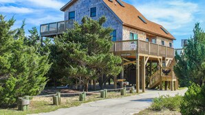Et toetagers hus med en træterrasse og et overdækket udeområde.