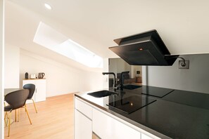 Une cuisine moderne dotée d’un plan de travail noir, d’une hotte intégrée et d’un puits de lumière.