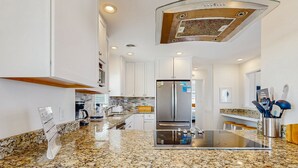 A modern kitchen with granite countertops, stainless steel appliances, and white cabinetry. - Fun beachfront home w/shared pool, WiFi, private washer & dryer, central AC (Avon)