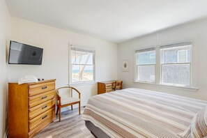 A bedroom with a bed, a wooden dresser, a chair, and a television mounted on the wall. - Fun beachfront home w/shared pool, WiFi, private washer & dryer, central AC (Avon)