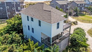 A multi-story building with a flat roof, surrounded by greenery and a view of the beach. - Semi-Ocean Front Retreat with Full Kitchen, Wifi, Outdoor Shower and A/C (Avon)