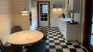 Une cuisine avec un carrelage à motifs, des placards blancs, une table à manger avec des chaises et une fenêtre.