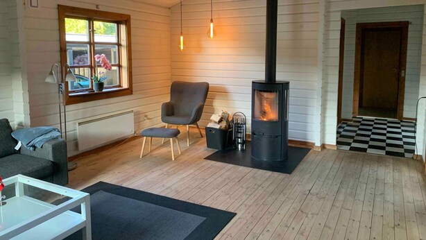 Un salon chaleureux avec un poêle à bois, un fauteuil confortable, un canapé et une petite table.
