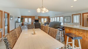 A spacious kitchen with a central island, wooden cabinetry, and a large dining table with patterned cushions. - Oceanfront home with central AC, ocean view, private hot tub, & pool (Avon)