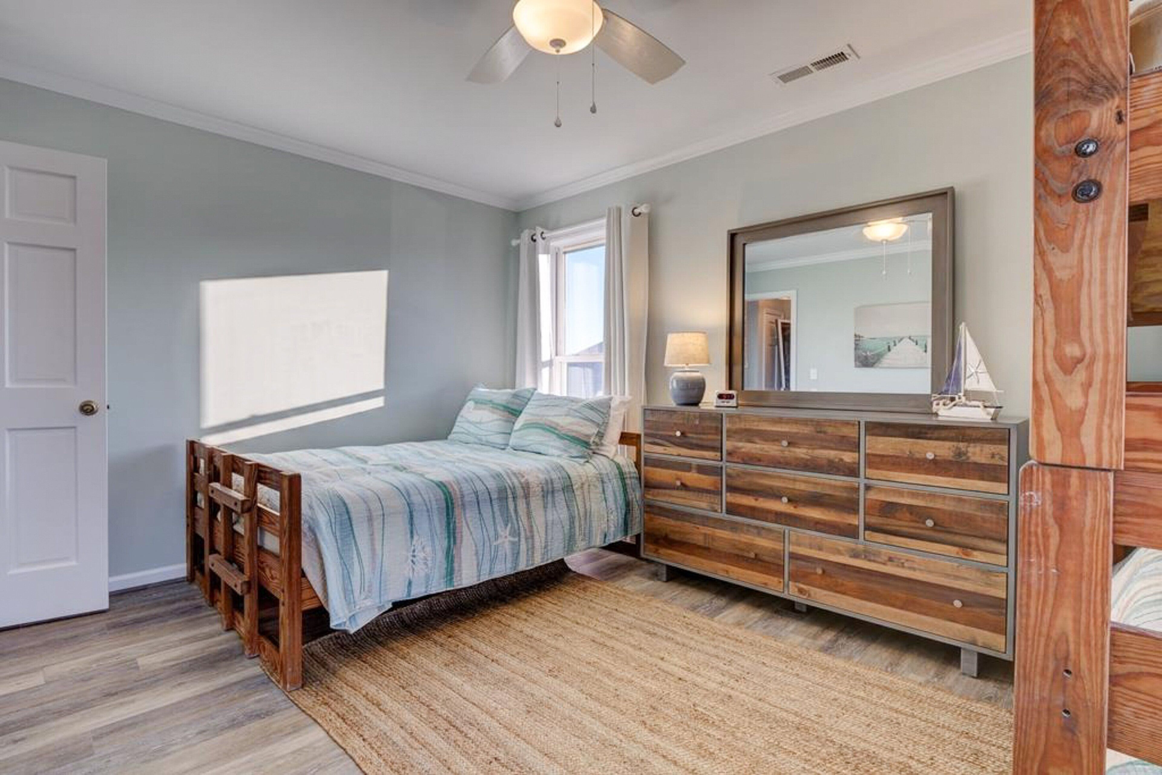 A bedroom with a bed, dresser, and a ceiling fan.
