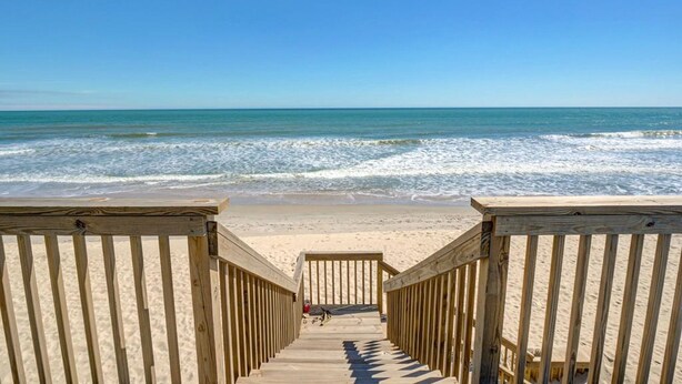 A wooden boardwalk leading to a sandy beach with the ocean in the background. - Stunning beachfront home with ocean-view decks and direct beach access in Surf City (Surf City)