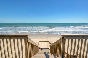 A wooden boardwalk leading to a sandy beach with the ocean in the background. - Stunning beachfront home with ocean-view decks and direct beach access in Surf City (Surf City)