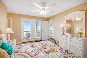 A bedroom with a bed, dresser, ceiling fan, and a view of the outdoors. - Spacious Oceanfront Retreat with Private Beach Access, Elevator, Game Room & Incredible Views (Surf City)