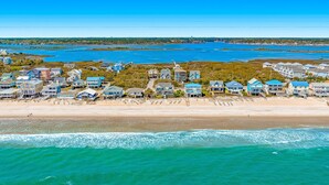 A coastal residential area with houses along the beach, a clear view of the ocean, and a distant shoreline.