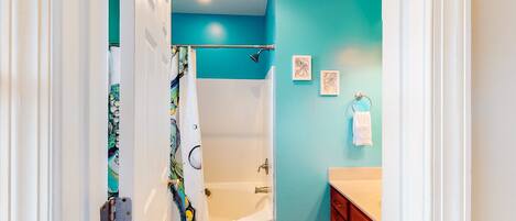 A bathroom with a bathtub, a shower, and a vanity with a sink.