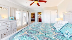 A bedroom with a bed, a ceiling fan, a dresser, and a view of the hallway. - Waterfront Condo w/ Free WiFi, Central AC, Private Washer/Dryer, Shared Pool (Hatteras)