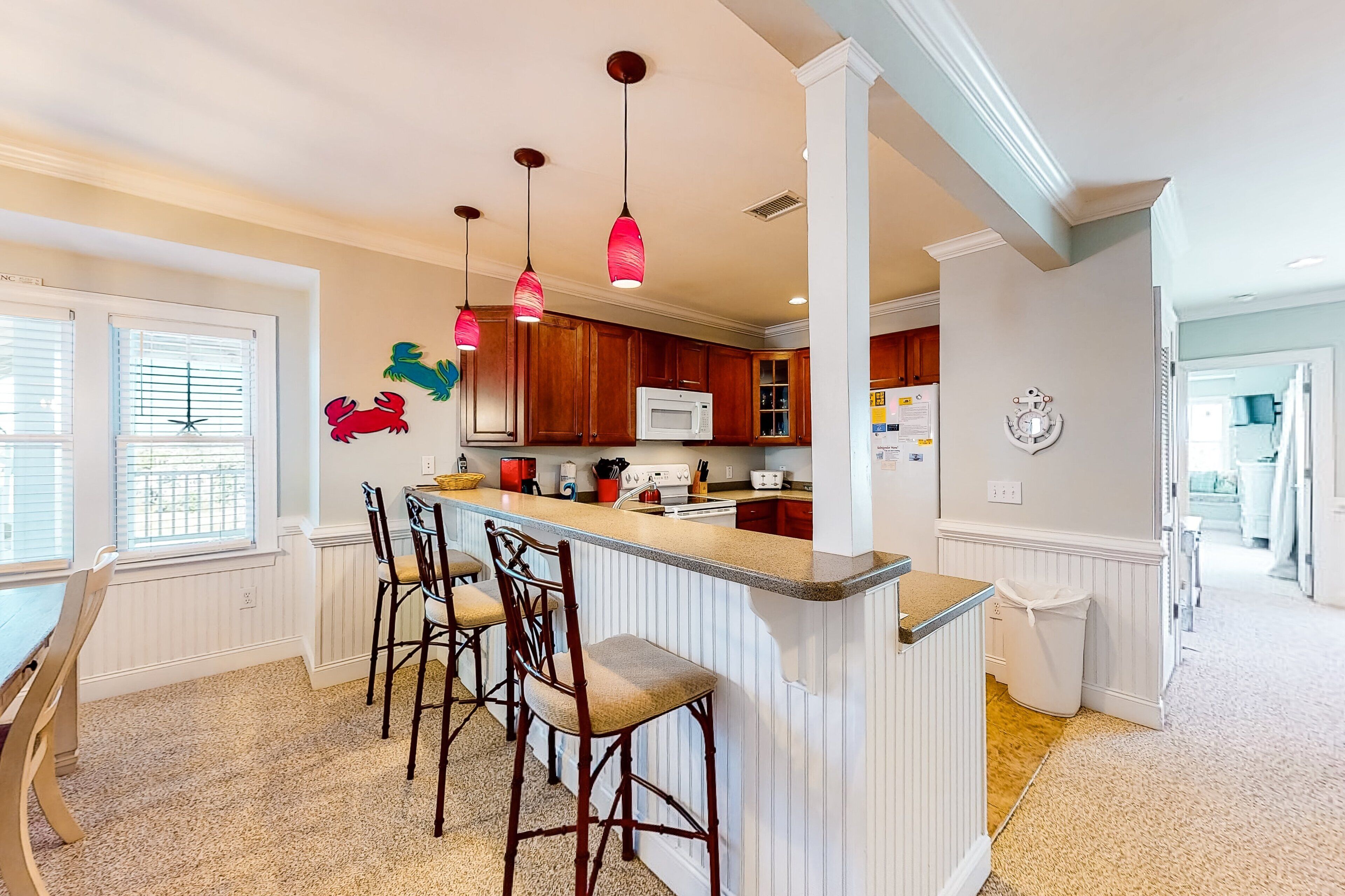 Una cocina con isla central, armarios de madera y luces colgantes.
