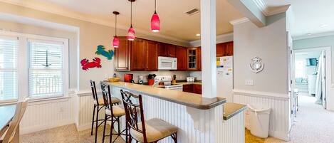 Una cocina con isla central, armarios de madera y luces colgantes.