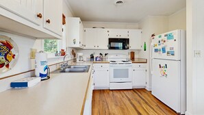 Une cuisine avec des meubles blancs, un four à micro-ondes, un réfrigérateur et un plancher en bois.