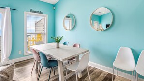 A dining area with a white table, blue chairs, and a potted plant. - Beachfront home with beach access, community pool, foosball table, ocean views (Surf City)