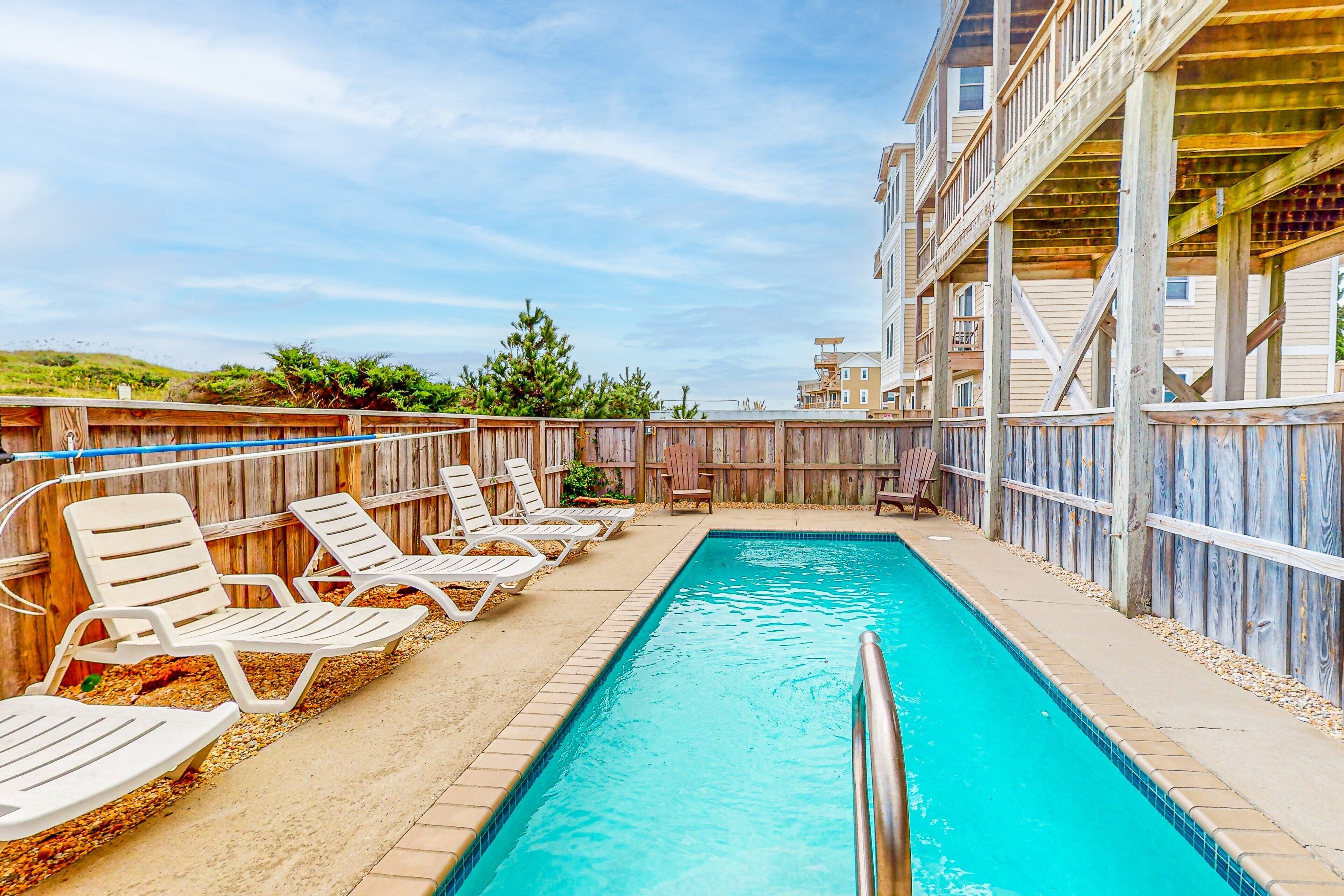 A swimming pool with lounge chairs and a wooden deck.