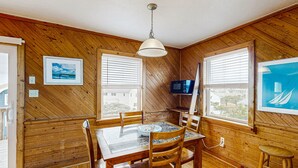 A wooden-paneled dining room with a table and chairs, a hanging light fixture, and two windows with blinds. - Tarpon Drive Hideaway B:Dog-friendly duplex w/Balcony (Avon)