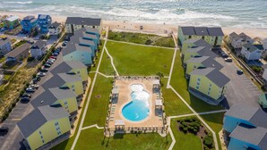 An aerial view of a coastal hotel with a central swimming pool, multiple buildings, and a beach in the background. - Surf City condo with community pool & direct beach access! (Surf City)