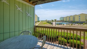 A wooden deck with a table and chairs, overlooking a pool and buildings. - Surf City condo with community pool & direct beach access! (Surf City)