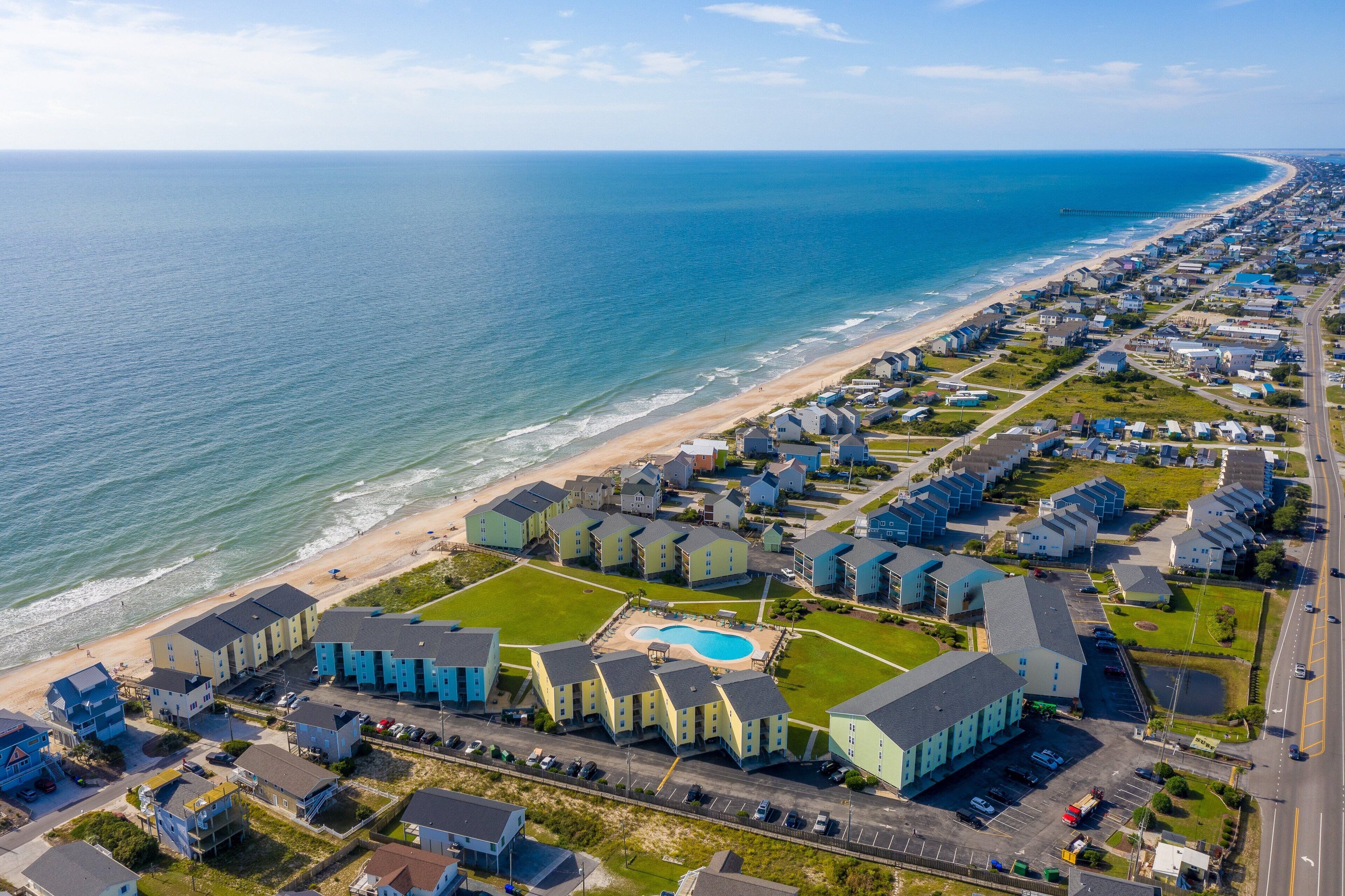 Vista aérea de una zona residencial costera con casas, una playa y una piscina.