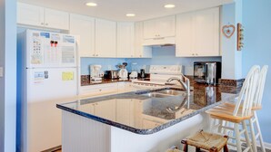 A modern kitchen with white cabinets, a granite countertop, and a stainless steel sink. - Surf City condo with community pool & direct beach access! (Surf City)