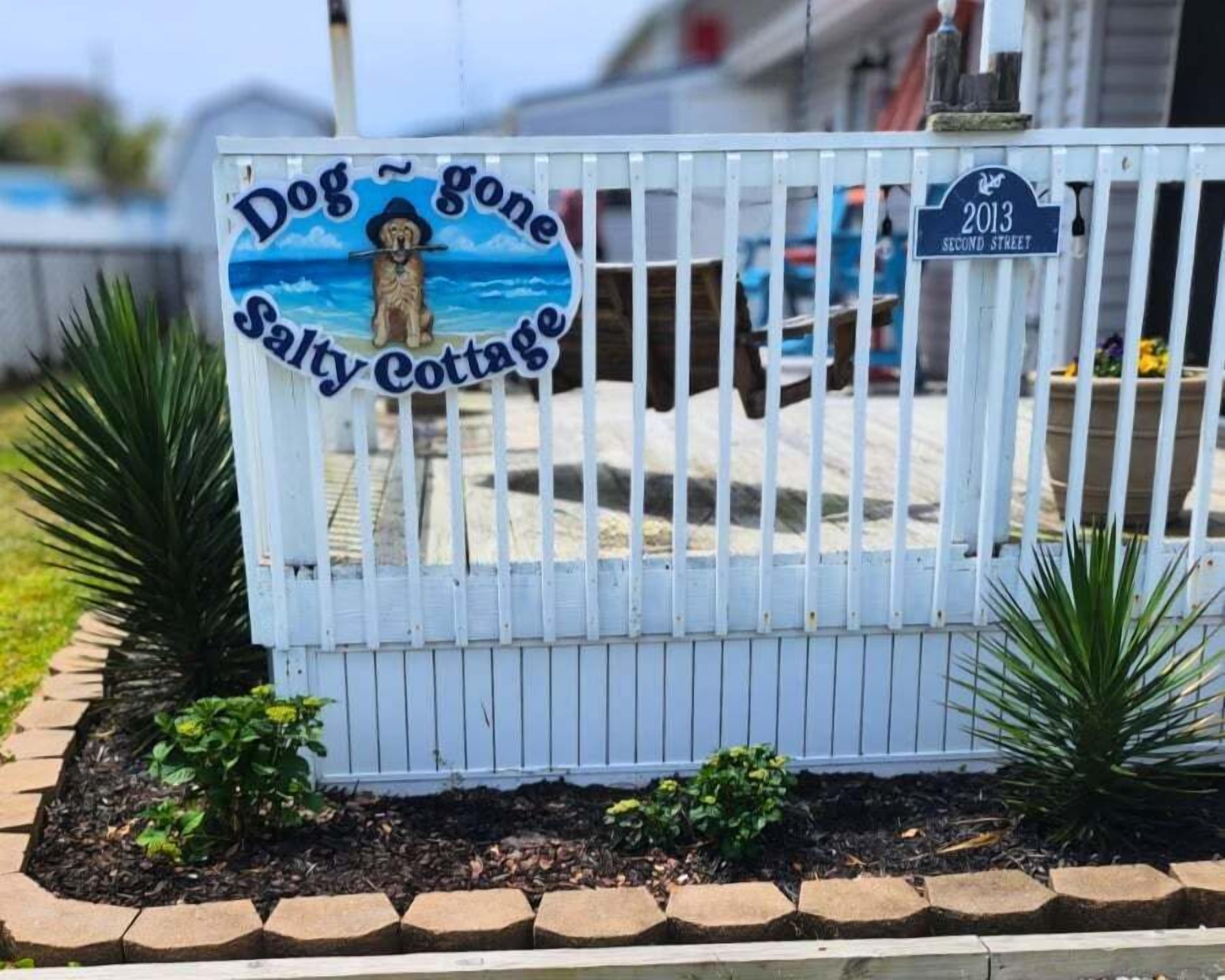 A gated entrance with a sign reading 'Dog Gone Salty Cottage' and a street sign indicating '2013 SECOND STREET.'