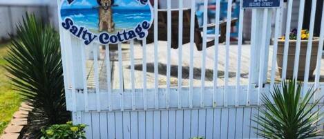 A gated entrance with a sign reading 'Dog Gone Salty Cottage' and a street sign indicating '2013 SECOND STREET.'