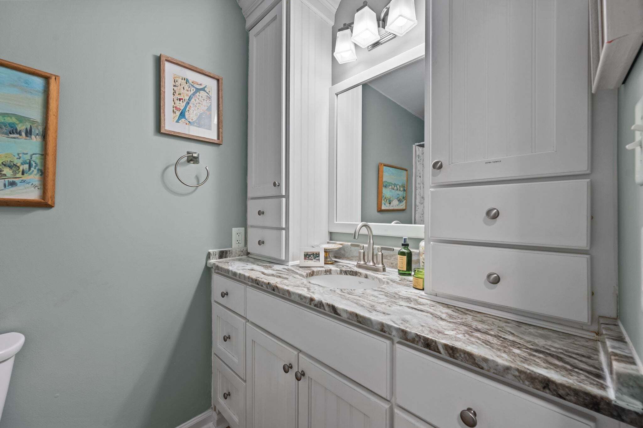A bathroom with a marble countertop, a large mirror, and a sink.