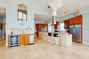 A modern kitchen with a central island, wooden cabinets, stainless steel appliances, and pendant lighting.