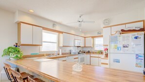 A modern kitchen with wooden countertops, white cabinets, and a central island with bar stools. - Oceanfront home with ocean views, beach access, tanning deck & private elevator (Surf City)