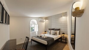 A modern bedroom with a bed, bedside tables, a desk, and a chair.