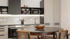 A modern kitchen with a central island, built-in appliances, and a dining area with four chairs.
