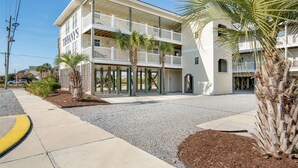 A two-story building with a white exterior, balconies, and palm trees. - Studio condo with ocean views, pool, deck, & central AC (Surf City)