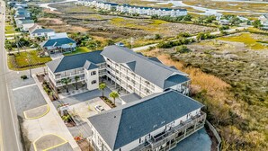 A large, multi-story hotel with a central courtyard and multiple balconies. - Studio condo with ocean views, pool, deck, & central AC (Surf City)