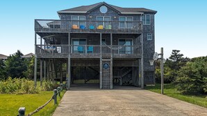 A multi-story building with a balcony, a basketball hoop, and a sign indicating a parking area. - SEMI-OCEANFRONT-5 BR, 3 Full & 1 Half Bath-just two lots from the beach walkway (Avon)