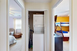 A laundry room with a washing machine and dryer, a bed with a bunk bed, and a small seating area with a chair and a table. - Coastal home close walk to the beach and local attractions (Surf City)