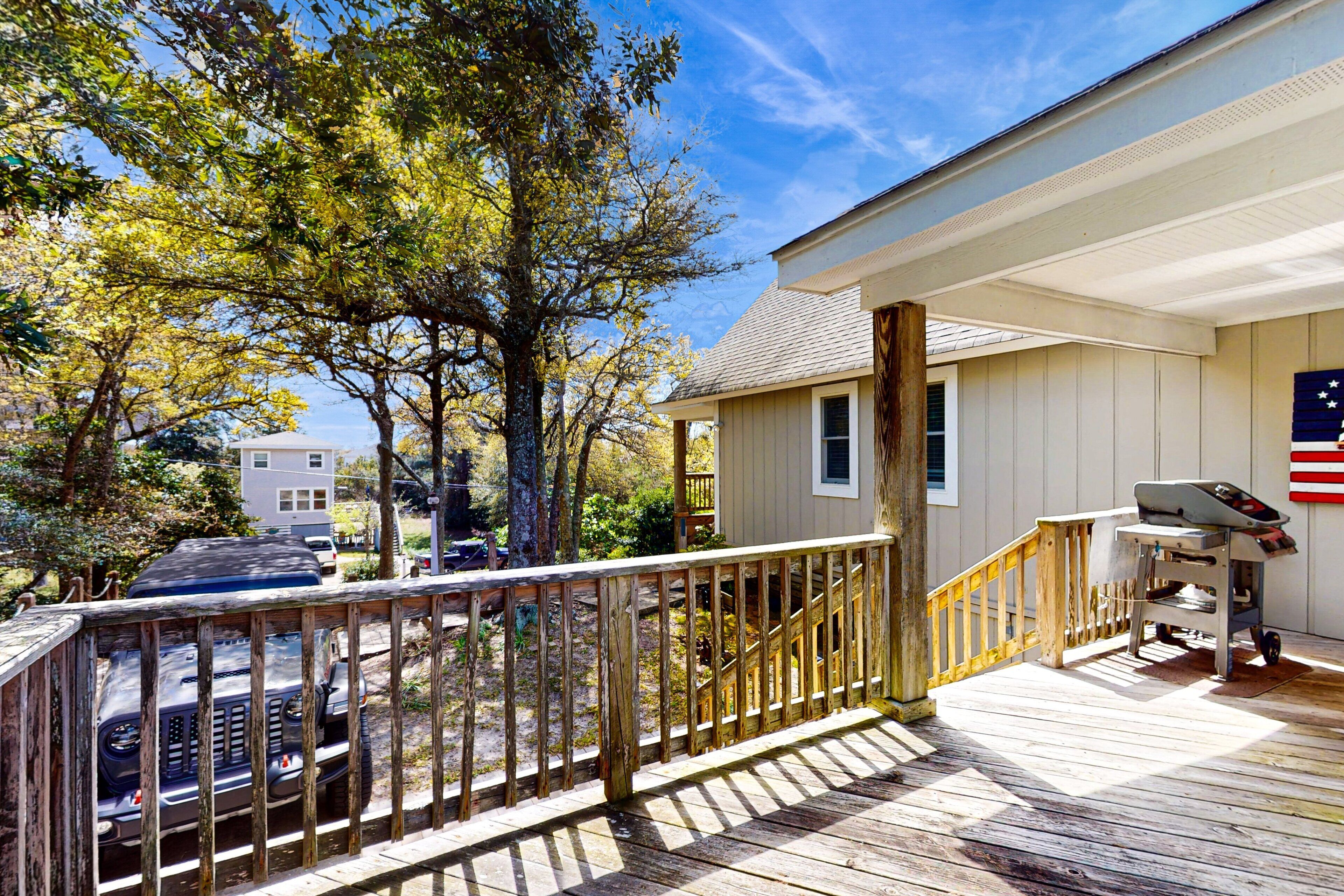 A wooden deck with a railing, a covered porch, and a small outdoor seating area with a table and chairs.