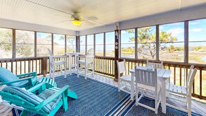 A covered outdoor seating area with chairs and tables, large windows, and a ceiling fan. - Dog-friendly House w/Water View, Free WiFi, AC, Private Hot Tub (Frisco)