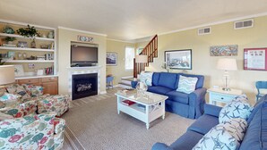 A living room with a fireplace, blue sofas, a coffee table, and a bookshelf. - Dog-friendly House w/Water View, Free WiFi, AC, Private Hot Tub (Frisco)